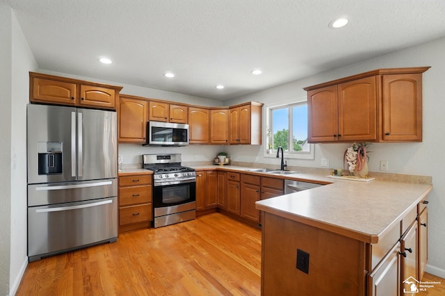 4853 Southpointe Pkwy, Monroe, MI 48161 - kitchen with stainless steel appliances, a sink, a peninsula, brown cabinetry, and light countertops
