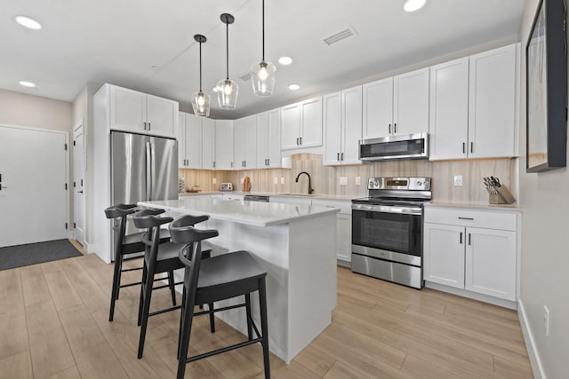 708 Randolph St, Traverse City, MI 49684 - kitchen with stainless steel appliances, a breakfast bar, light countertops, recessed lighting, and light wood finished floors