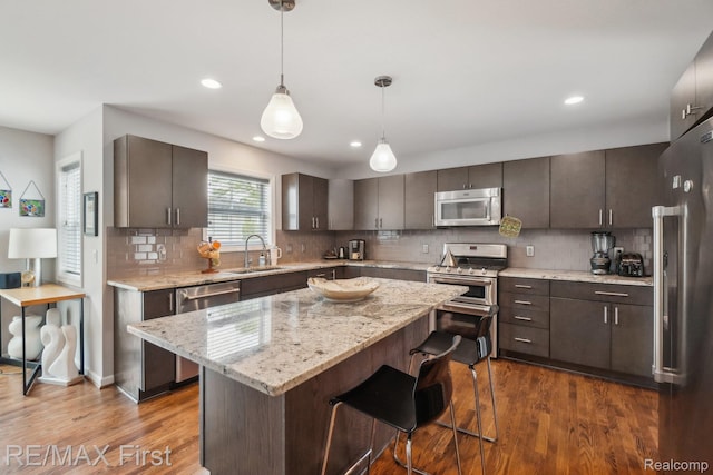 2681 Buckingham Ave, Birmingham, MI 48009 - kitchen with appliances with stainless steel finishes, a sink, dark wood-style flooring, backsplash, and a breakfast bar area