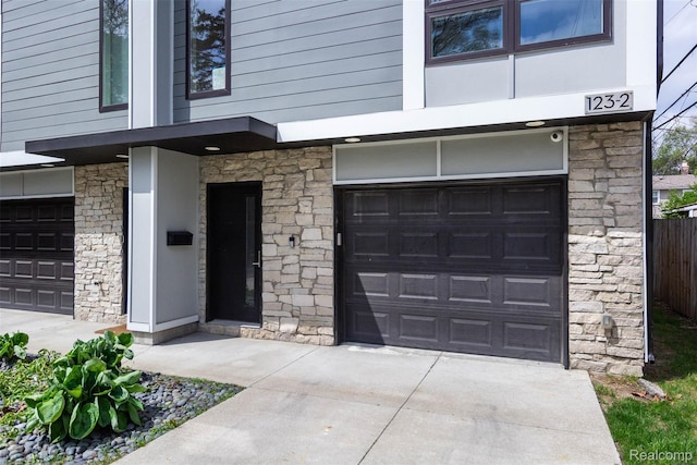 123 Mason Ct Unit 2, Royal Oak, MI 48067 - view of exterior entry featuring stone siding, a garage, and driveway