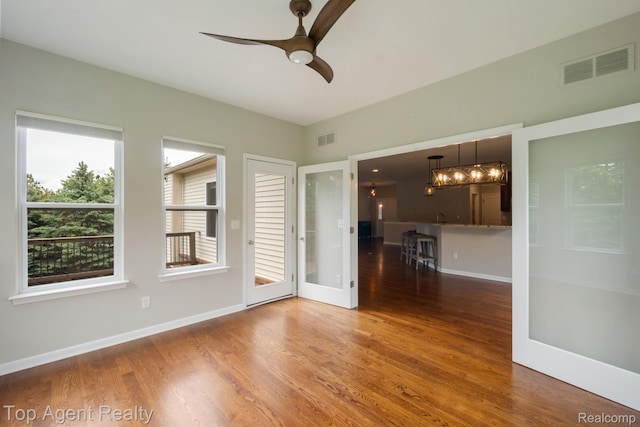 109 Willow Lake Dr, Oxford, MI 48371 - spare room featuring wood finished floors, baseboards, a ceiling fan, and a chandelier