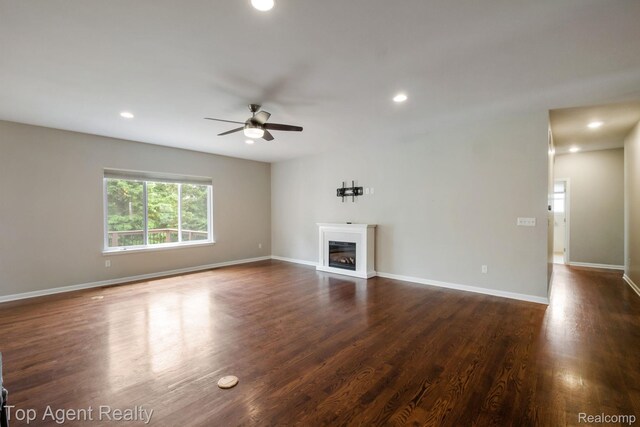 109 Willow Lake Dr, Oxford, MI 48371 - unfurnished living room featuring a ceiling fan, a glass covered fireplace, recessed lighting, dark wood-type flooring, and baseboards