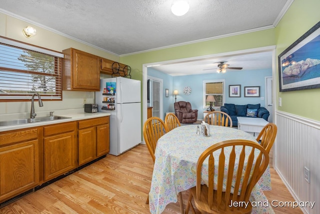 2058 N White Birch Dr, Mears, MI 49436 - kitchen with a sink, freestanding refrigerator, light wood-style floors, a textured ceiling, and brown cabinets