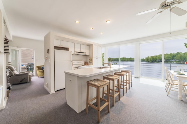 15657 Lakeview Dr, Buchanan, MI 49107 - kitchen with white appliances, carpet, under cabinet range hood, light countertops, and an island with sink