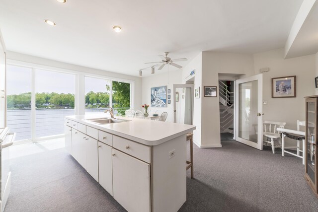 15657 Lakeview Dr, Buchanan, MI 49107 - kitchen featuring a sink, carpet, light countertops, white cabinets, and an island with sink
