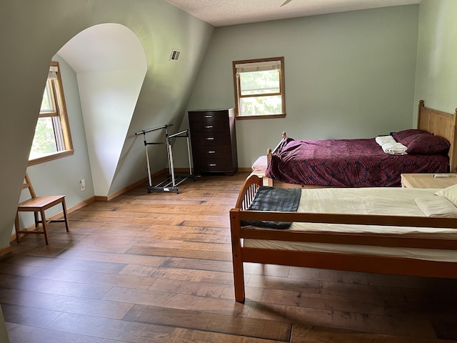 7033 N M-140, Watervliet, MI 49098 - bedroom featuring hardwood / wood-style floors, multiple windows, arched walkways, baseboards, and a textured ceiling