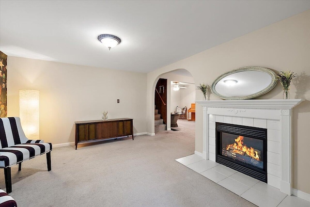 236 Simpson St, Grass Lake, MI 49240 - living area featuring carpet floors, a tiled fireplace, stairs, arched walkways, and ceiling fan