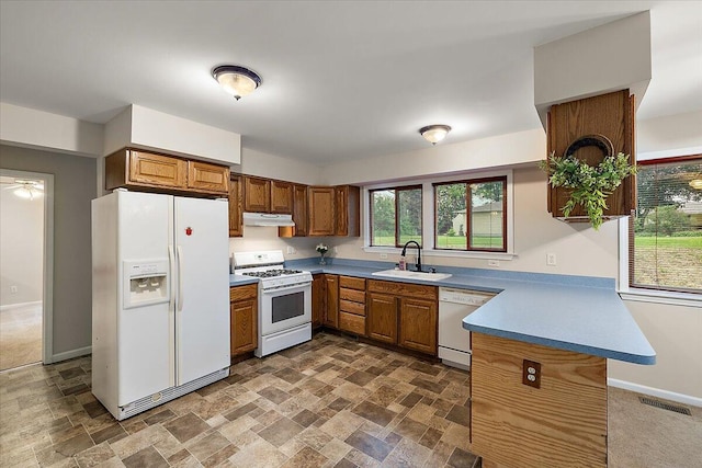236 Simpson St, Grass Lake, MI 49240 - kitchen with white appliances, a sink, under cabinet range hood, brown cabinetry, and a peninsula