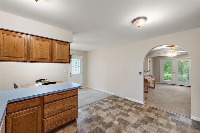 236 Simpson St, Grass Lake, MI 49240 - kitchen featuring arched walkways, brown cabinetry, baseboards, stone finish flooring, and carpet