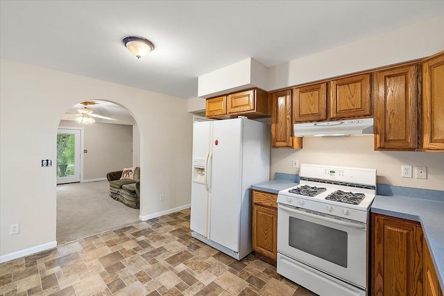 236 Simpson St, Grass Lake, MI 49240 - kitchen with under cabinet range hood, white appliances, stone finish flooring, arched walkways, and brown cabinets