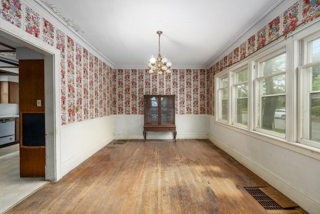 554 Ethel Ave SE, Grand Rapids, MI 49506 - unfurnished dining area with a chandelier, wainscoting, wallpapered walls, wood finished floors, and crown molding