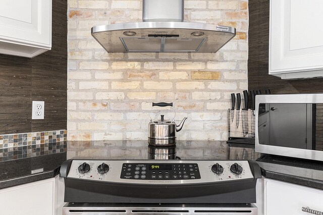 810 Cottageview Dr, Traverse City, MI 49684 - kitchen featuring island exhaust hood, stainless steel appliances, dark countertops, and white cabinets
