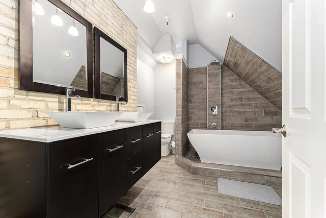 810 Cottageview Dr, Traverse City, MI 49684 - bathroom with double vanity, lofted ceiling, wood finished floors, a freestanding tub, and toilet