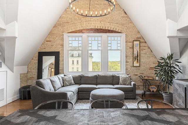 810 Cottageview Dr, Traverse City, MI 49684 - living area with brick wall, vaulted ceiling, a chandelier, and wood finished floors