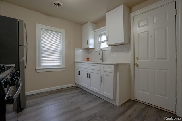 26640 Pattow St, Roseville, MI 48066 - kitchen with range with gas stovetop, white cabinets, wood finished floors, light countertops, and a sink