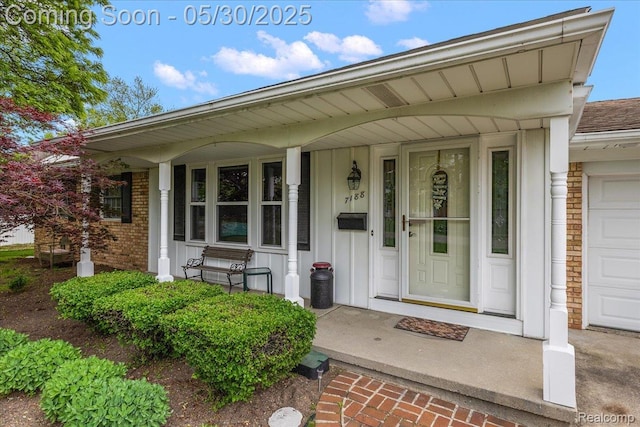 7188 Vicksburg Cir, Shelby Twp, MI 48317 - view of exterior entry featuring board and batten siding, brick siding, covered porch, and a garage