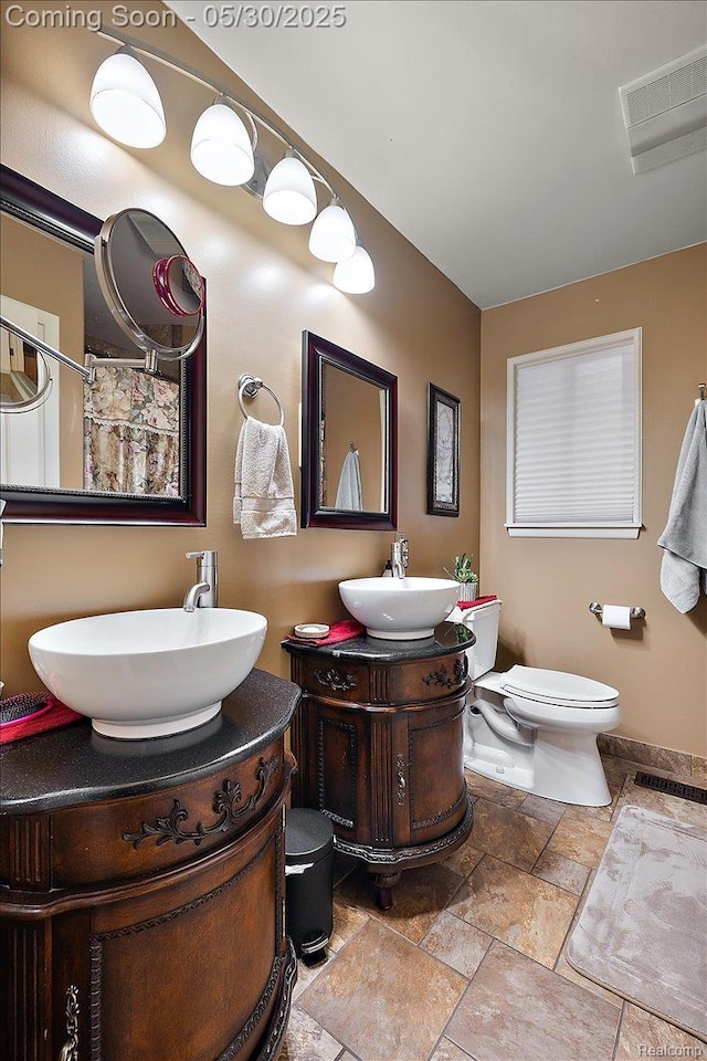 7188 Vicksburg Cir, Shelby Twp, MI 48317 - bathroom featuring stone tile floors, vanity, toilet, and baseboards