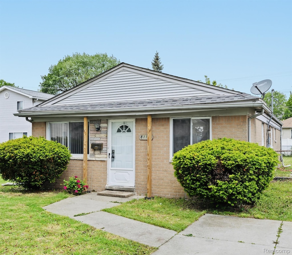 8111 Timken Ave, Warren, MI 48089 - bungalow featuring brick siding, a front yard, and roof with shingles
