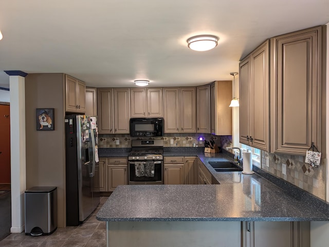 6919 Abrahamson Rd, Ludington, MI 49431 - kitchen featuring appliances with stainless steel finishes, a sink, a peninsula, tasteful backsplash, and dark tile patterned flooring