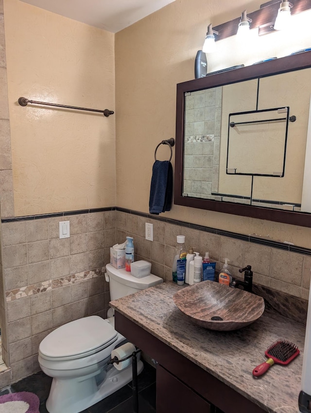 6919 Abrahamson Rd, Ludington, MI 49431 - bathroom featuring toilet, vanity, tile walls, and a wainscoted wall