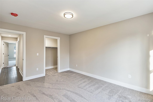 527 Indian Oaks Dr, Howell, MI 48843 - unfurnished bedroom with dark colored carpet, baseboards, and a walk in closet