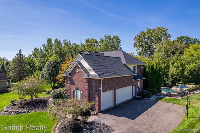 1804 Morgan Lake Ct, Brighton, MI 48114 - view of property exterior with brick siding, asphalt driveway, an attached garage, an outdoor pool, and a yard