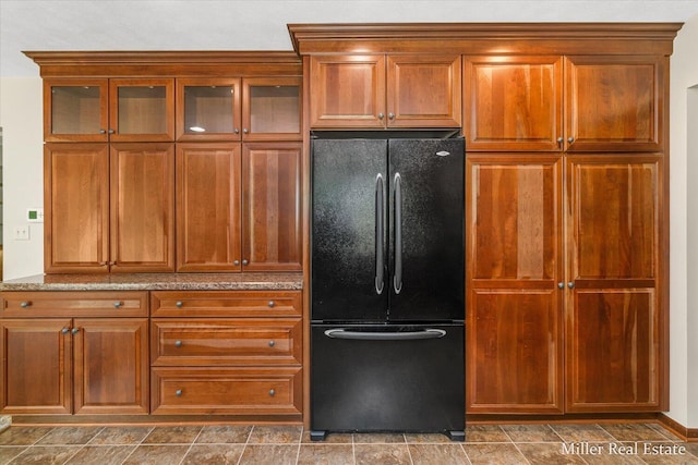 4700 M-79, Nashville, MI 49073 - kitchen with freestanding refrigerator, light stone countertops, and brown cabinets