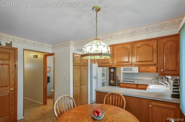 13936 Grove Park Dr, Sterling Heights, MI 48313 - kitchen featuring white appliances, a sink, a peninsula, pendant lighting, and brown cabinetry