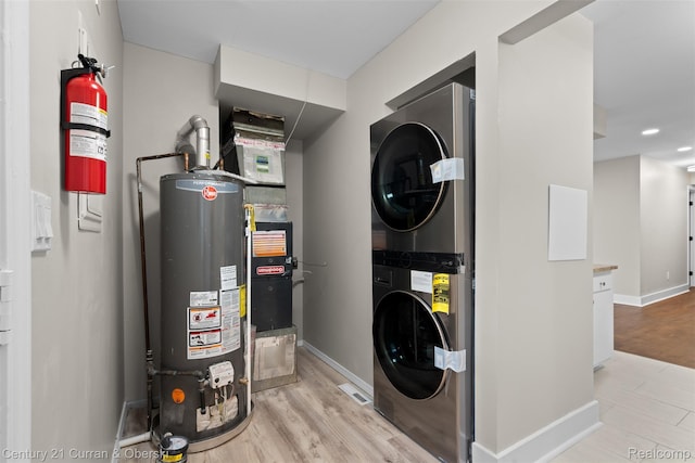 6262 Garden Ct, Warren, MI 48091 - laundry area with gas water heater, estacked washer and dryer, baseboards, wood finished floors, and heating unit