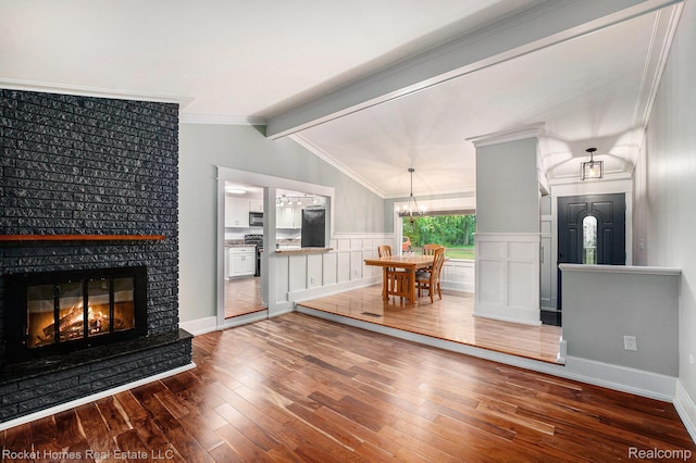 35825 Oakwood Ln, Westland, MI 48186 - living room featuring wood-type flooring, a large fireplace, a chandelier, wainscoting, and crown molding
