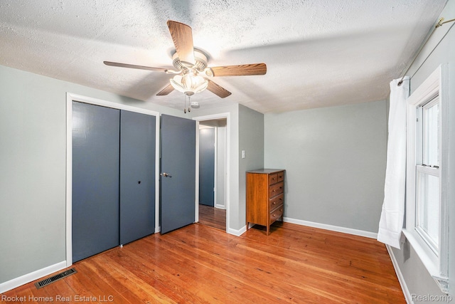 35825 Oakwood Ln, Westland, MI 48186 - unfurnished bedroom with light wood-style flooring, a textured ceiling, a closet, baseboards, and ceiling fan