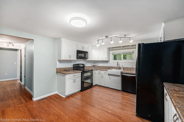 35825 Oakwood Ln, Westland, MI 48186 - kitchen featuring black appliances, a sink, wood finished floors, backsplash, and white cabinetry