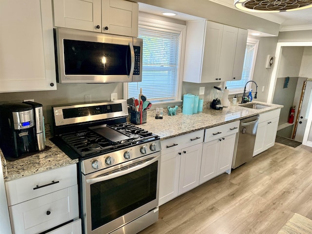 5547 Davison Rd, Davison, MI 48446 - kitchen featuring stainless steel appliances, a sink, white cabinetry, ornamental molding, and light wood-type flooring