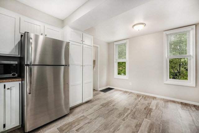 1535 Colorado Ave SE, Grand Rapids, MI 49507 - kitchen with stainless steel appliances, white cabinetry, healthy amount of natural light, and baseboards