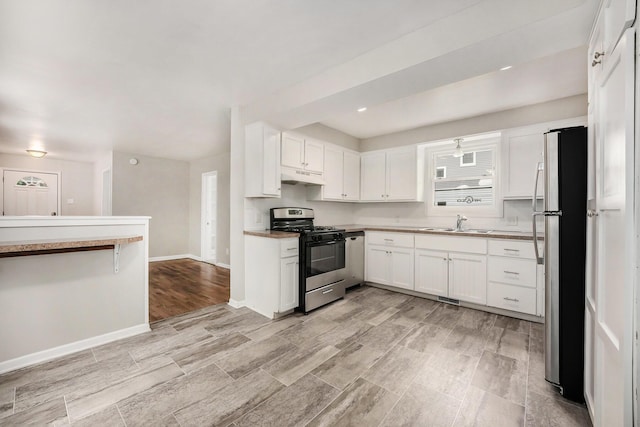1535 Colorado Ave SE, Grand Rapids, MI 49507 - kitchen with appliances with stainless steel finishes, a sink, white cabinetry, and under cabinet range hood