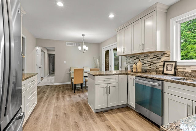 4766 Quarton Rd, Bloomfield, MI 48302 - kitchen with appliances with stainless steel finishes, a peninsula, decorative backsplash, light wood-style floors, and a chandelier
