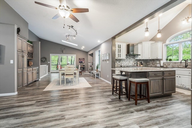 5400 Laura Dr, Shelbyville, MI 49344 - kitchen featuring vaulted ceiling, wall chimney exhaust hood, wood finished floors, a sink, and healthy amount of natural light