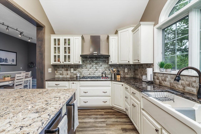 5400 Laura Dr, Shelbyville, MI 49344 - kitchen featuring wall chimney exhaust hood, a sink, tasteful backsplash, wood finished floors, and dark stone counters