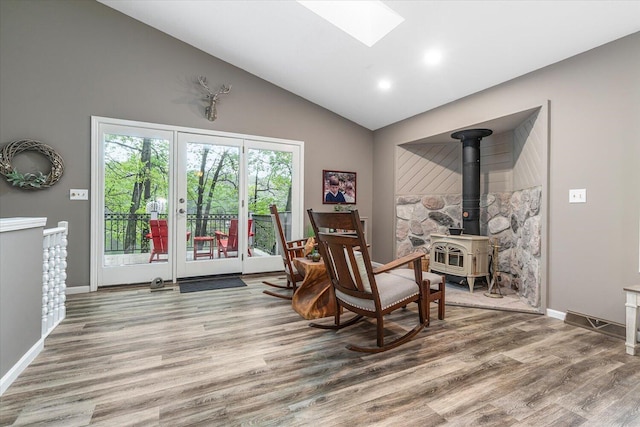 5400 Laura Dr, Shelbyville, MI 49344 - sitting room with wood finished floors, a wood stove, high vaulted ceiling, baseboards, and a skylight