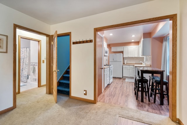 210 E Palmer Ave, Jackson, MI 49203 - kitchen with white appliances, white cabinetry, light colored carpet, backsplash, and a sink