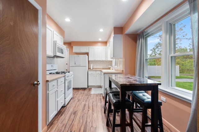 210 E Palmer Ave, Jackson, MI 49203 - kitchen with white appliances, plenty of natural light, light wood finished floors, backsplash, and recessed lighting