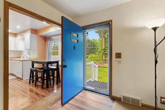 210 E Palmer Ave, Jackson, MI 49203 - doorway to outside featuring light wood-style flooring, baseboards, recessed lighting, and a sink