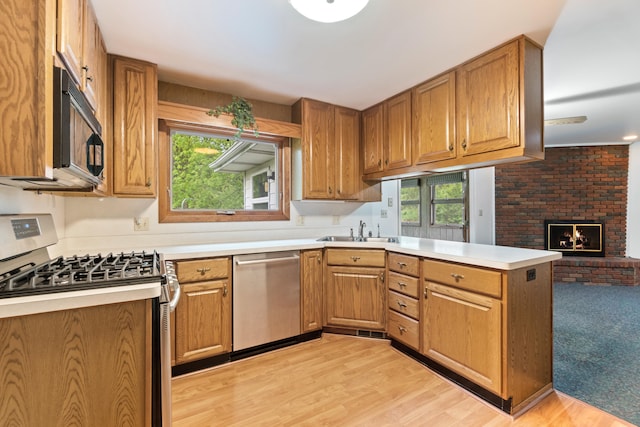 2141 N Parker Rd, Dexter, MI 48130 - kitchen featuring stainless steel appliances, a sink, a peninsula, light countertops, and a brick fireplace