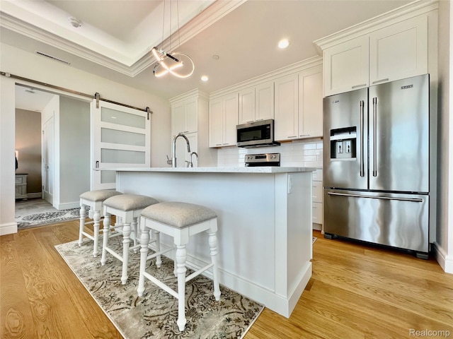 201 Beers St Unit 44, Port Huron, MI 48060 - kitchen featuring appliances with stainless steel finishes, light wood-style floors, white cabinetry, an island with sink, and recessed lighting