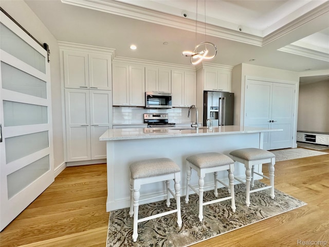 201 Beers St Unit 44, Port Huron, MI 48060 - kitchen featuring stainless steel appliances, a breakfast bar, a center island with sink, white cabinets, and crown molding