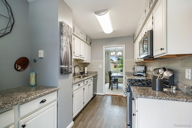 14850 La Grande Plz, Warren, MI 48088 - kitchen with stainless steel appliances, white cabinetry, a sink, dark wood-style flooring, and decorative backsplash