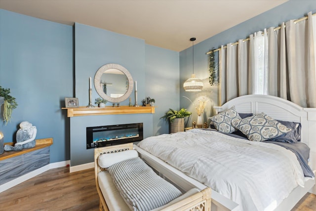 1010 6th St, Bay City, MI 48708 - bedroom featuring wood finished floors, a glass covered fireplace, and baseboards