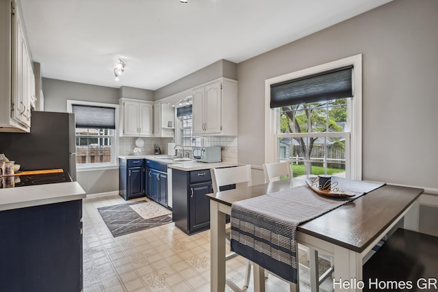 2052 Gorham Dr SE, East Grand Rapids, MI 49506 - kitchen featuring blue cabinets, healthy amount of natural light, white cabinets, and decorative backsplash