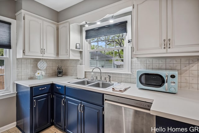 2052 Gorham Dr SE, East Grand Rapids, MI 49506 - kitchen with stainless steel dishwasher, blue cabinetry, a sink, and healthy amount of natural light