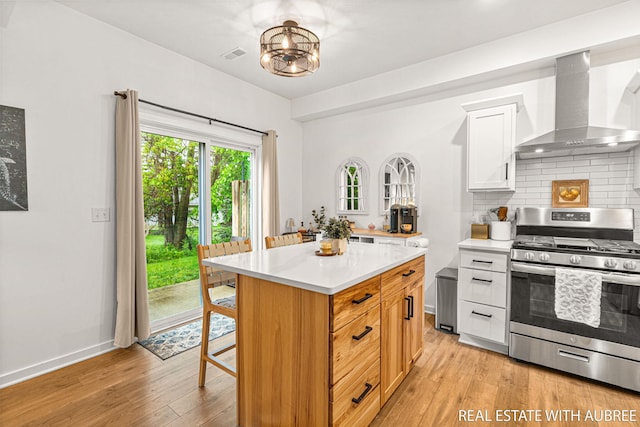 392 Harbor Town Ct Unit 2, Holland, MI 49423 - kitchen with gas stove, wall chimney exhaust hood, light countertops, tasteful backsplash, and a kitchen breakfast bar